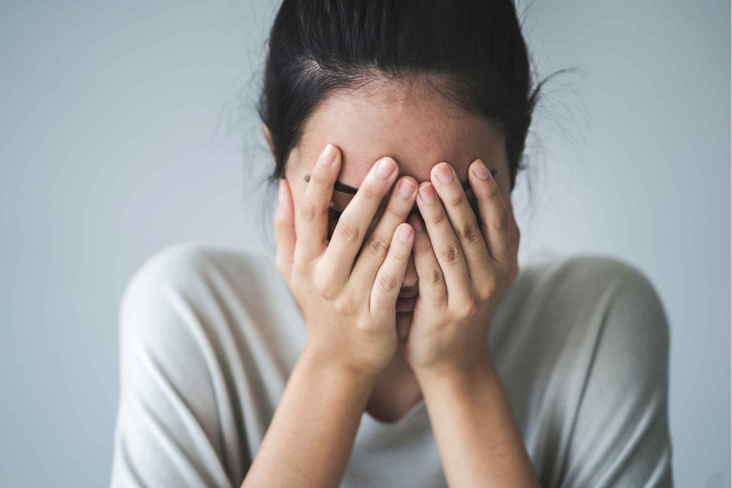 A woman covering her face with her hands.
